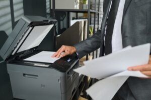 An office worker makes copies at a copier in a business setting. Everyday office documents can become important records in white collar crime defense strategies.
