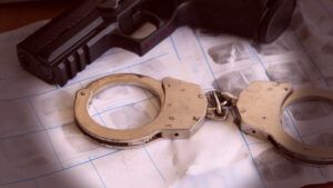 These handcuffs on a table represent the penalties that can follow gun charges, including jail time.