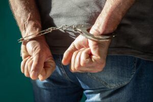 A person is in handcuffs during an arrest on gun charges. Gun charges are not always felonies, but they can lead to serious penalties.